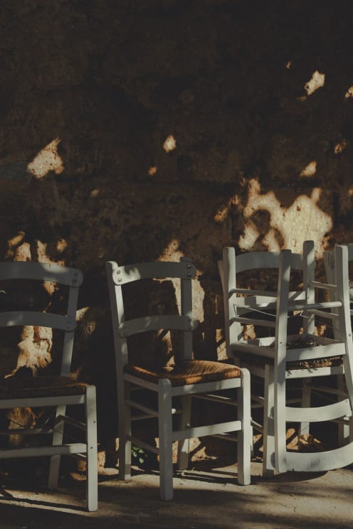 Whicker Chairs Along An Exterior Wall Shaded By Trees