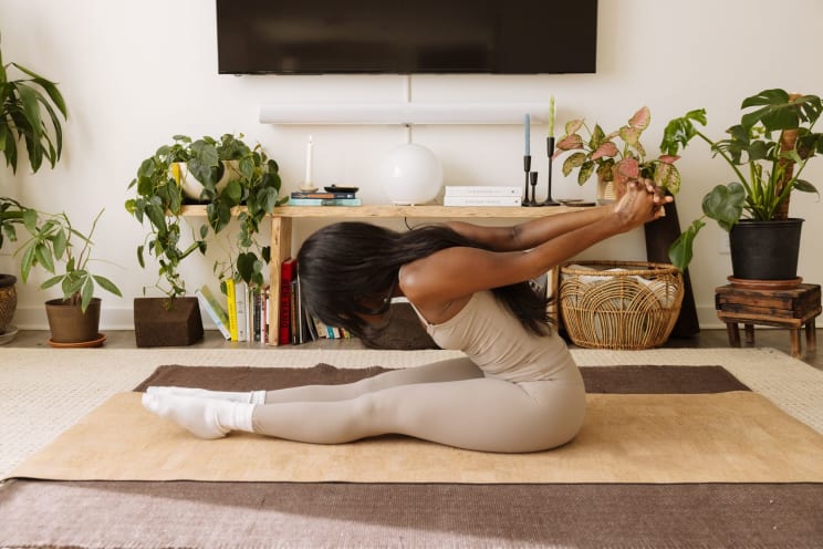 Woman Practicing Yoga At Home, Wearing A Tight Beige Outfit