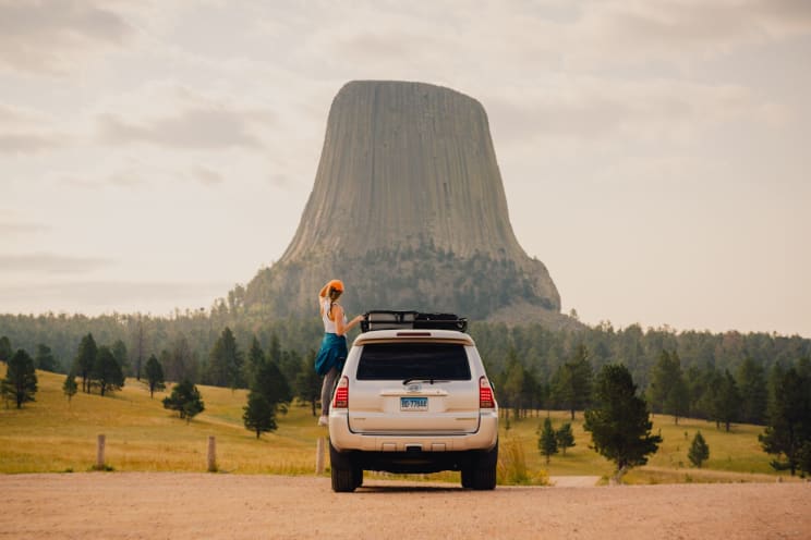 Woman Standing On The Side Of A Truck Looking At The Devils Tower National Monument