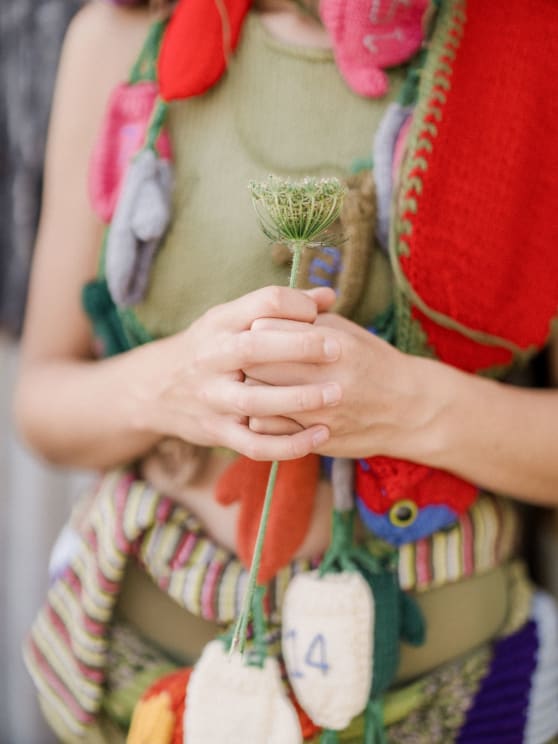 Woman Wearing Knit Accessories Holds A Flower While Standing Outdoors