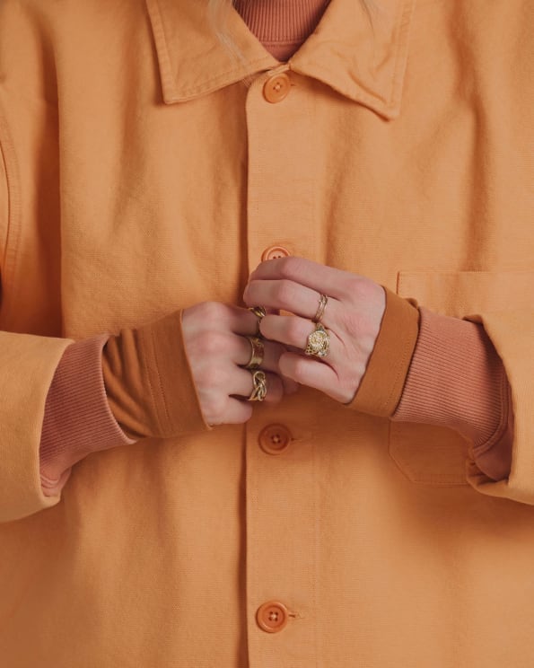 Close Up Of A Pair Of Hands With Golden Rings And Wearing Long-sleeved Orange Clothing