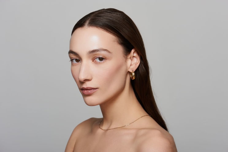 Bare Shouldered Woman With Long Dark Hair Turns Her Head To Look Into The Camera