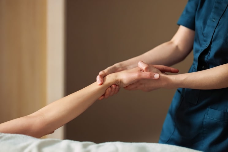 A Male Nurse Grips A Female Patient's Arm With Both Hands