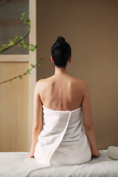 A Woman Sitting On A Bed In A Towel