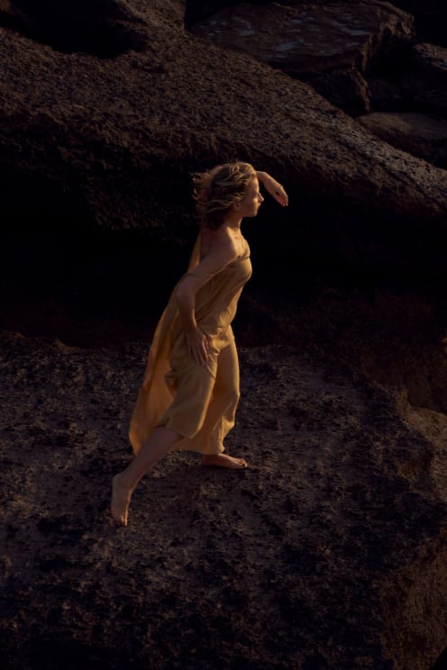 Woman In Flowing Dress Poses Among Rocks