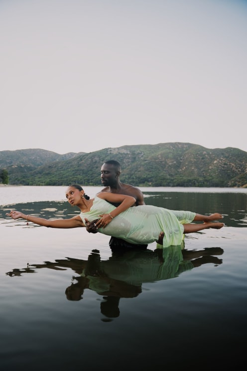 A Portrait Of A Man Holding A Woman In A Lake