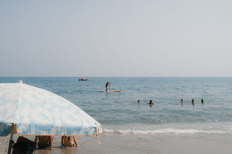 People On The Beach And In The Water As Boats Sail