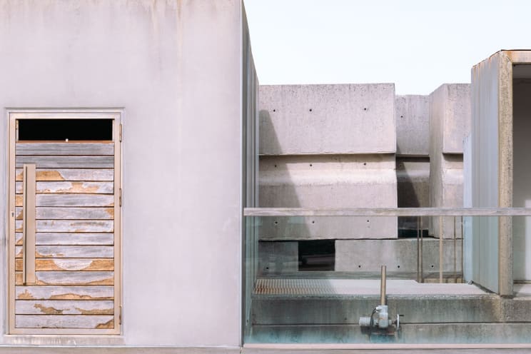 Distressed Wooden Door Next To A Concrete Structure With Glass Railing And Industrial Elements