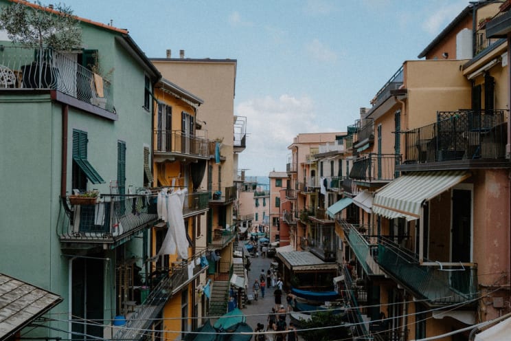 People Walk Along The Narrow Street Between Apartment Buildings On A Cloudy Day