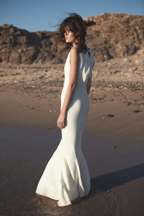 A Woman Standing On The Beach In A Dress