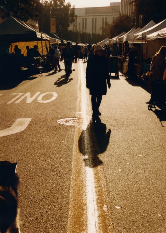 A Woman Walking In The Middle Of The Street On A Sunny Evening