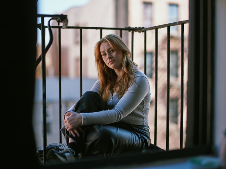 A Woman Sitting On A Balocony Outside