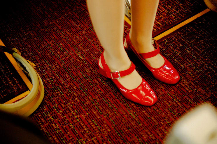 A Woman's Feet Wearing Red Leather Shoes