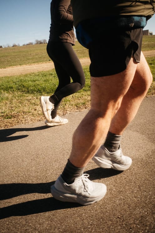Two People Jogging Outdoors On A Sidewalk