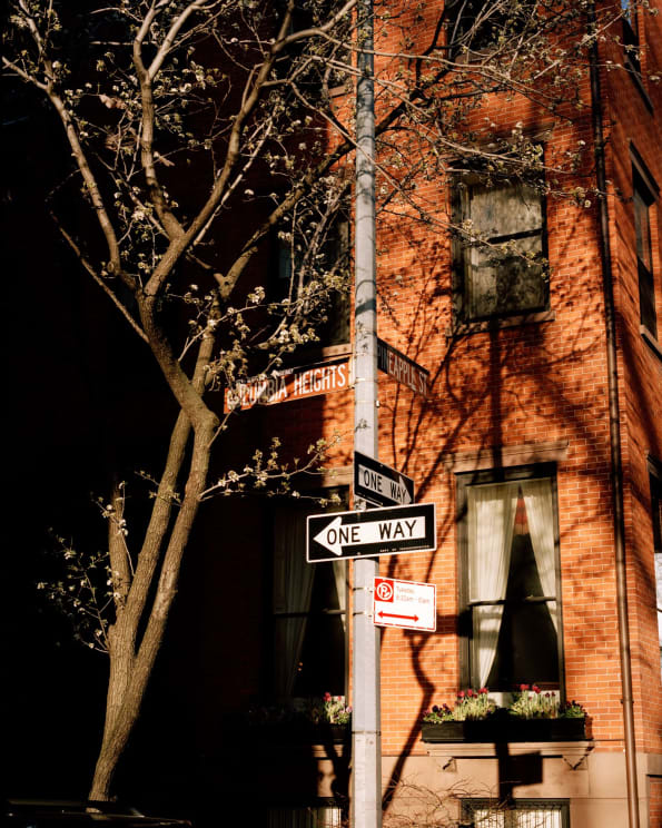 Street Signs Are In Front Of A Brick Apartment Building