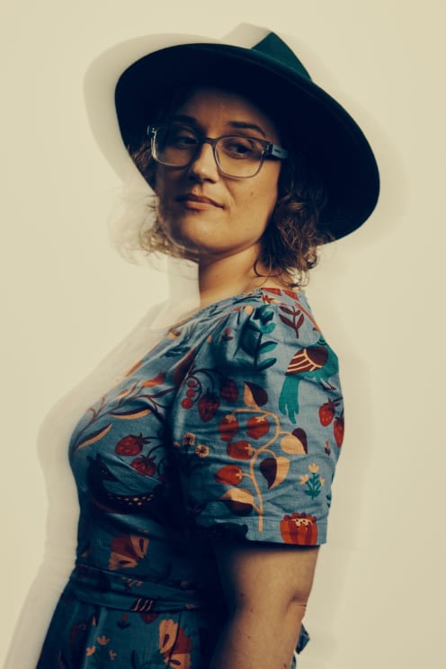 A Person Wearing A Dark Hat And A Quirky Dress Standing Up