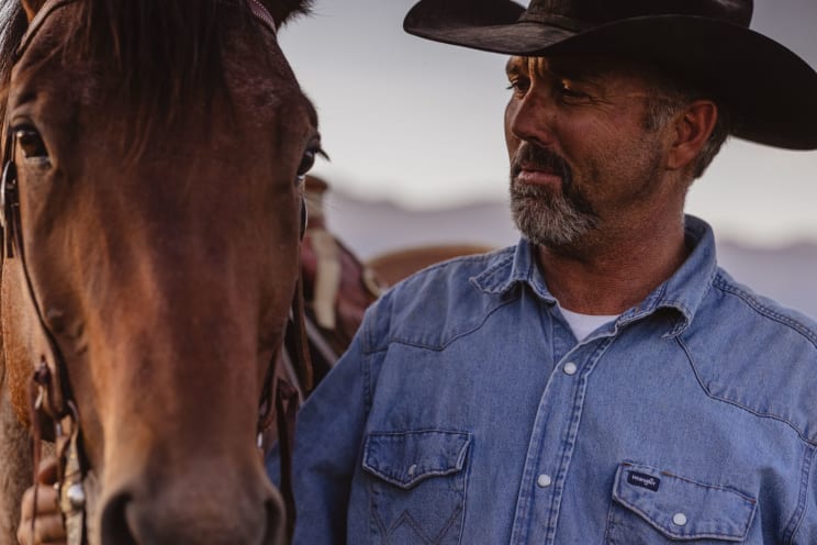 A Man On Horseback Gently Strokes His Horse