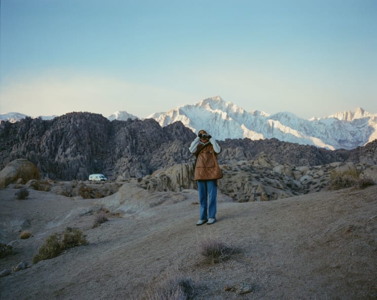 Woman Standing In A Wild Landscape Holding A Camera