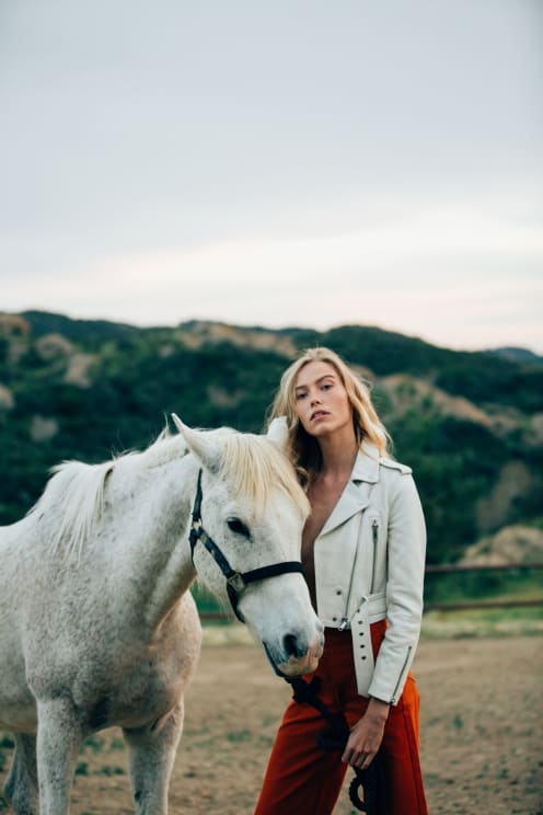 A Woman Proudly Stands Beside A Horse With A Mountain Landscape In The Background