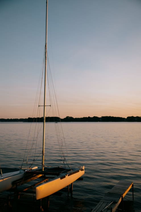 Two Sailboats Docked On A Large Lake With A Vast Sky In The Background