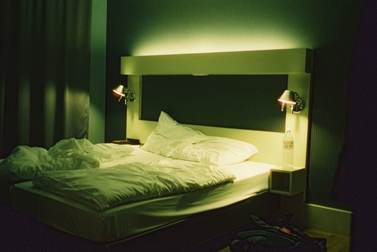 Bedroom With Messy Bed And Lamp On The Walls In A Hotel Room