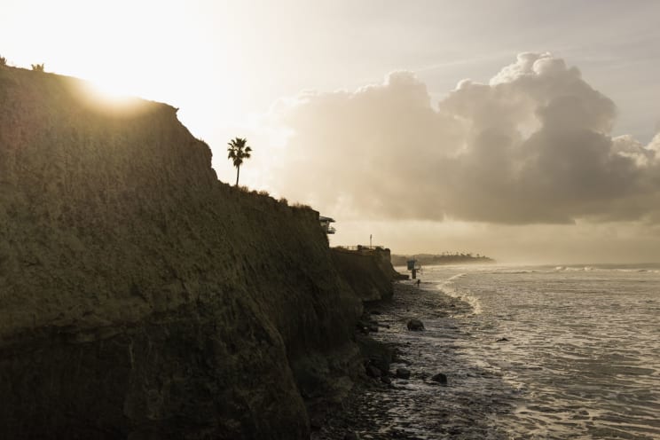 The Morning Sun Shining From Behind The Steep Rocky Ocean Coastline