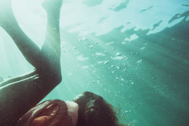 A Woman Falling Underwater Legs Above Her Head