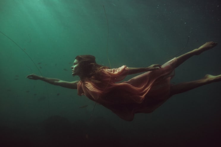 A Woman Swimming Underwater Wearing Swimwear And A Diving Mask