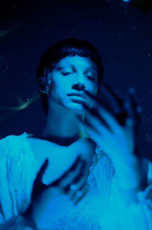 A Woman Under Blue Light Looking At Her Hands