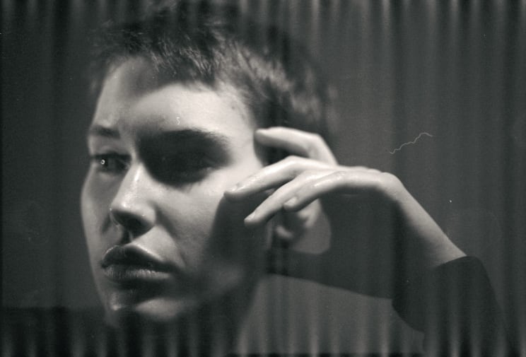 A Woman Rests Her Hand On The Side Of Her Face