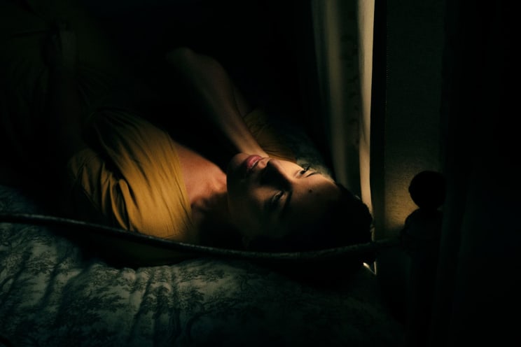 A Young White Woman Laying Down On A Bed In Daylight