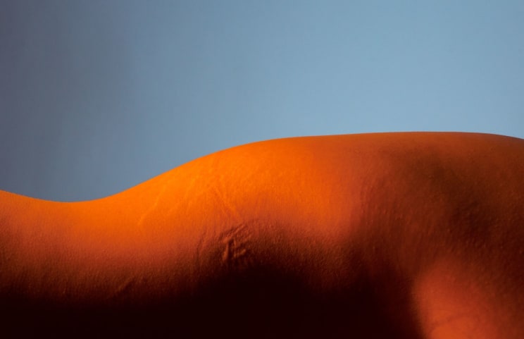 A Shot Of A Female Nude Waist Under Warm Orange Light
