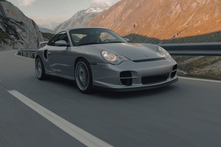 A Sports Car Drives On A Highway Next To A Mountain