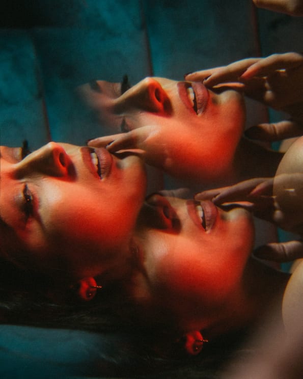 Young Woman With Makeup Lying On A Blue Sofa Under Contrast Light In A Triple Exposure Portrait