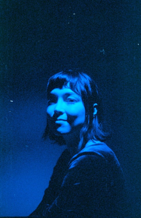 A Darkhaired Woman Sitting Down Under Blue Lights