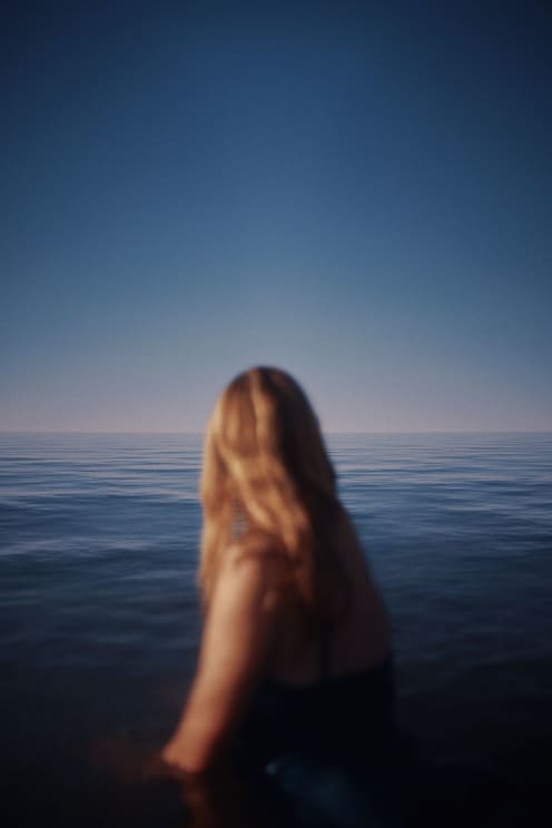 A Woman Standing On The Beach At Sunset