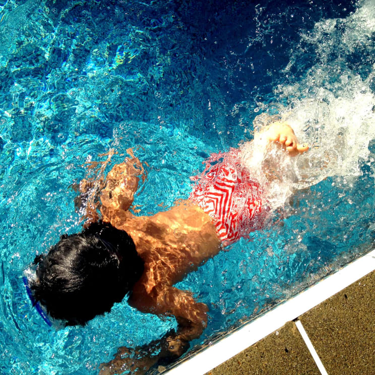 A Little Boy Swimming In A Pool