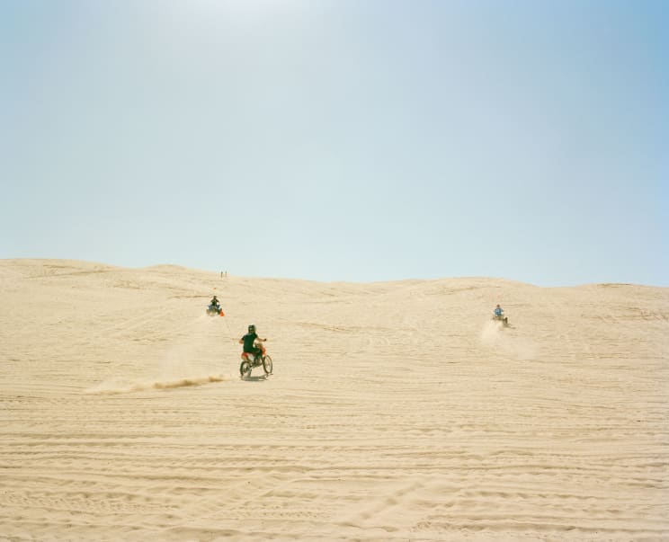 People Riding Motor Vehicles In A Sandy Landscape