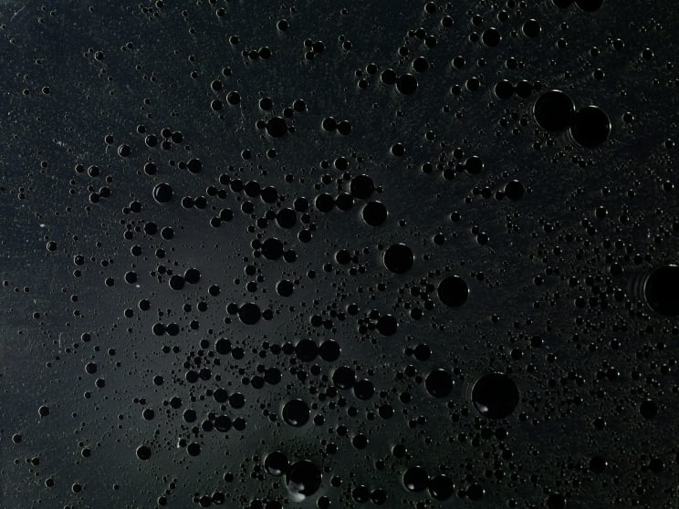 Hundreds Of Black Liquid Droplets Against A Black Background