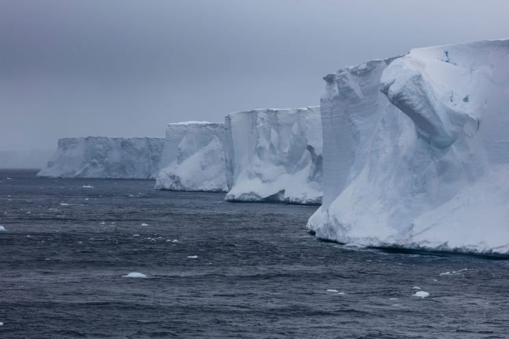 A Frozen Mountain And Icy Landscape With Water And Sky