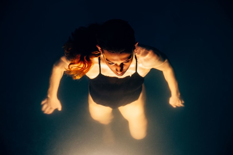 A Woman Swimming In A Pool At Night