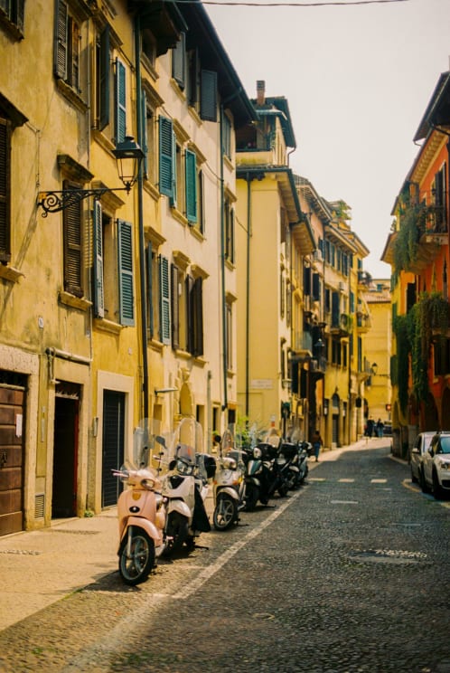 Motor Scooters Parked Along A Narrow Street Lined With Historic Apartment Buildings