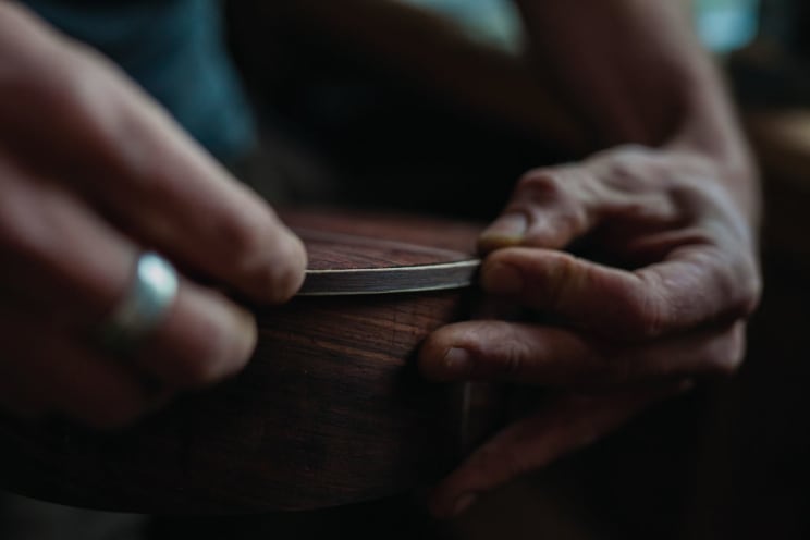 Craftsperson Presses Metal Rim On Circular Wooden Box