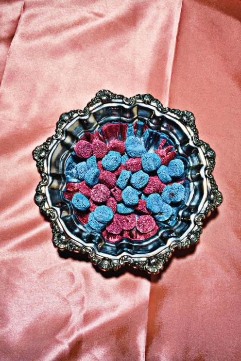 A Dish Filled With Blue And Purple Candies On A Velvet Bed Sheet Indoors