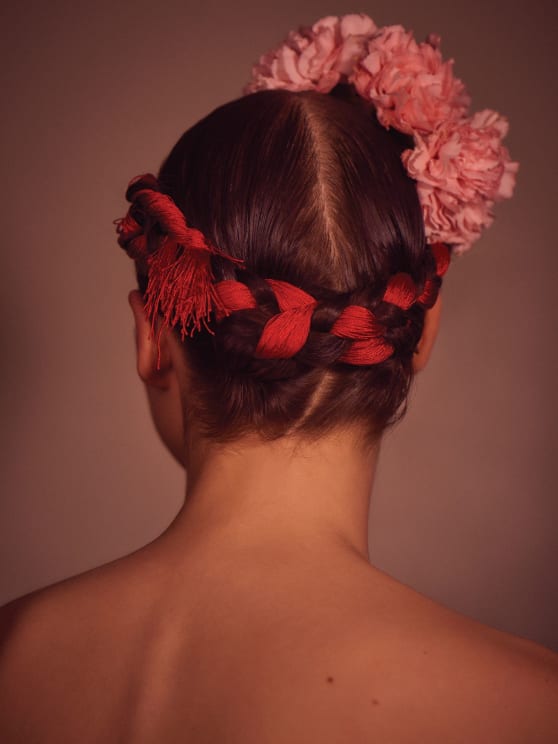 A Young Woman With Braided Hair And A Floral Hair Accessory