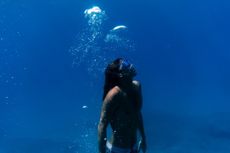 A Man Diving Underwater On A Sunny Day