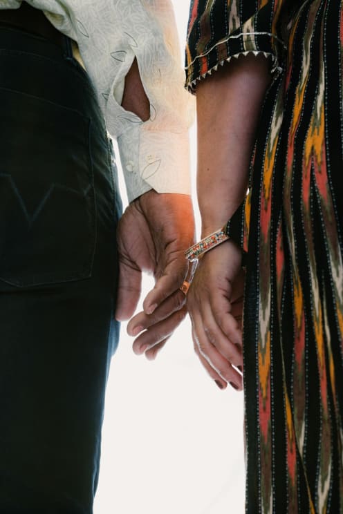 A Couple In Dressy Clothes Stand Side By Side, Their Hands Not Touching