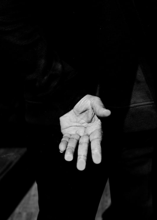 The Palm Of A Man's Hand With A Long Pinky Fingernail Against Dark Long Sleeve Clothing