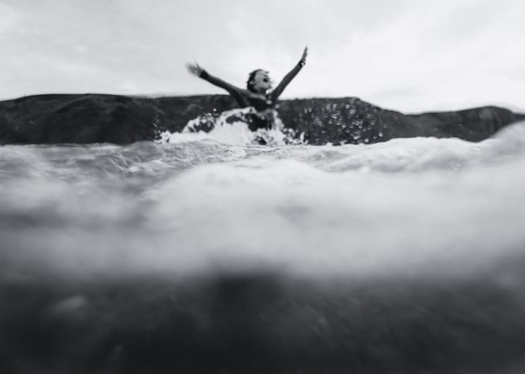 A Woman Surfer Jumping Out Of The Water And Cheering
