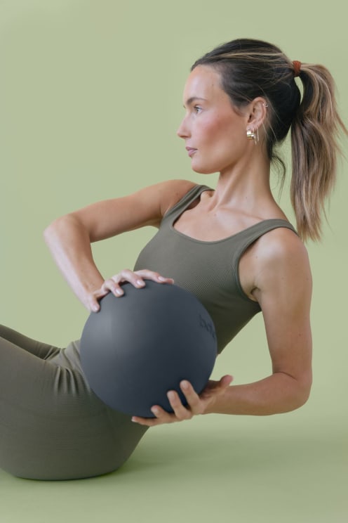 A Woman Doing Yoga Stretches While Holding A Weighted Ball